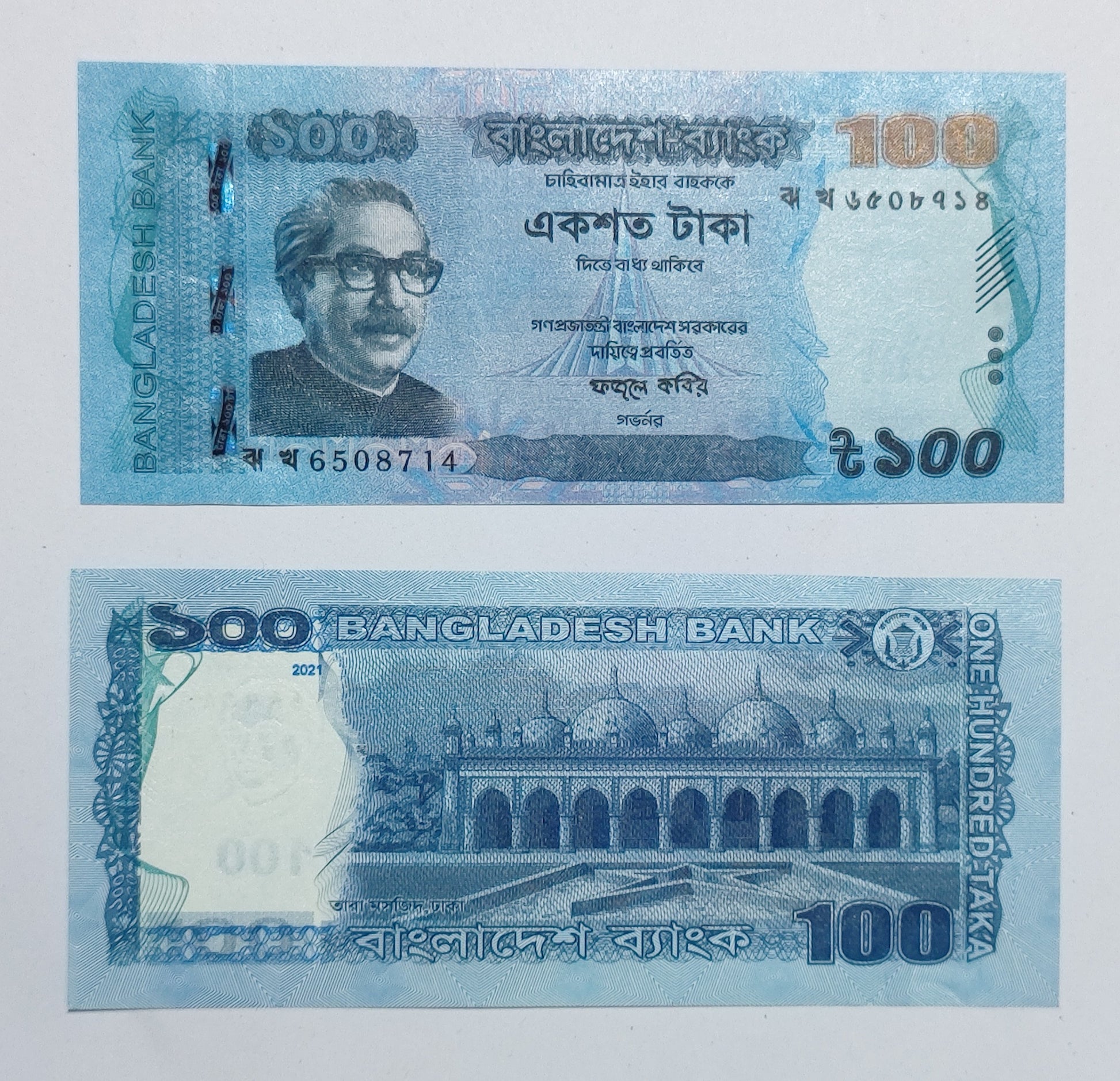 100 Taka banknote of Bangladesh with a portrait and architectural design on a light blue background